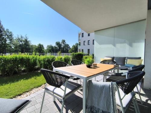un patio con tavolo e sedie in legno di Helikon Beach Apartment a Keszthely