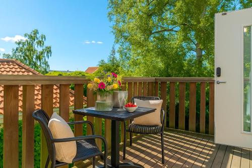 a patio table with chairs and flowers on a deck at Falsterbo Beachside Apartments in Skanör med Falsterbo