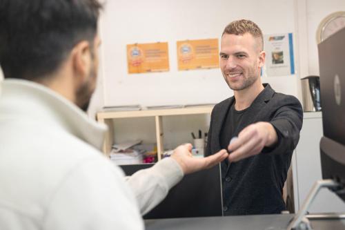a man shaking another mans hand in an office at K 357 - Low budget Hotel in Ratekau bei Lübeck in Ratekau