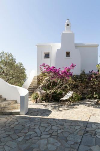 a white building with a lighthouse and purple flowers at SPITIA VASILI in Kapsálion
