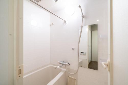 a white bathroom with a tub and a mirror at Otakihashi Pacifica Building in Tokyo