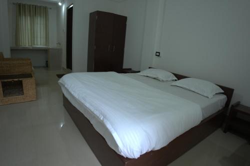 a bedroom with a large bed with white sheets at Traveller's Hostel by Spirit of Adventure, Dirang in Dirang Dzong
