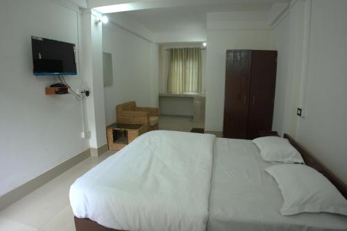 a bedroom with a white bed and a flat screen tv at Traveller's Hostel by Spirit of Adventure, Dirang in Dirang Dzong