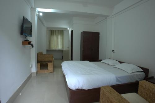 a bedroom with a large bed and a television at Traveller's Hostel by Spirit of Adventure, Dirang in Dirang Dzong