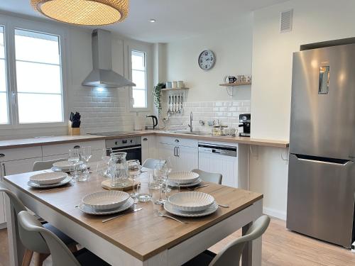 une cuisine avec une table avec des assiettes et des verres dessus dans l'établissement Le Fleury Chic - Centre - Tramway - 2 pers, au Mans