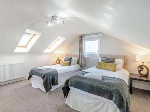 a attic bedroom with two beds and two windows at 5 Bed House -Sleeps 10- Hot Tub - Garden - Parking in Edinburgh