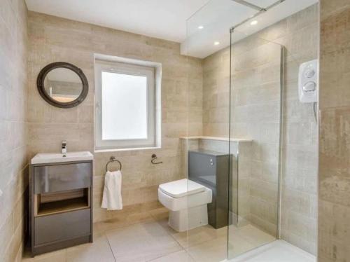 a bathroom with a toilet and a glass shower at 5 Bed House -Sleeps 10- Hot Tub - Garden - Parking in Edinburgh