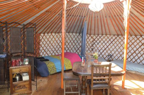 a room with a table and a bed in a yurt at Le portillon des fées in Sost