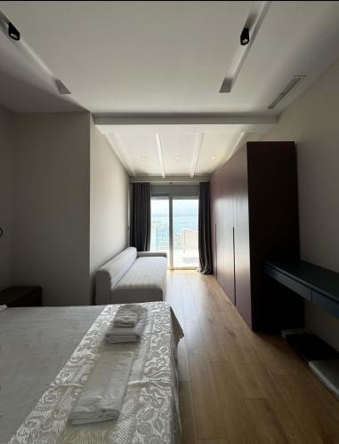 a bedroom with a bed and a couch and a window at Penthouse with Jackuzy in Sarandë