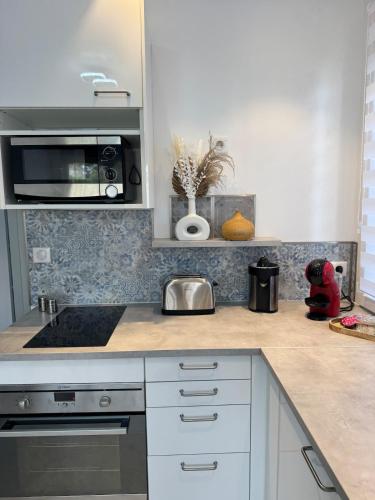 une cuisine avec des armoires blanches et un four à plaques de cuisson dans l'établissement magnifique T2 calme bord de mer, à La Ciotat