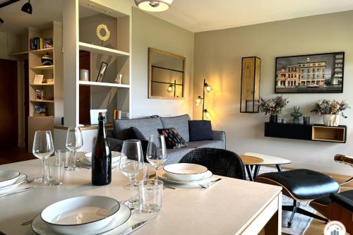- un salon avec une table, des verres à vin et un canapé dans l'établissement Le Golf de Pia - Vue Mer Panoramique - Parking, à Tourgéville