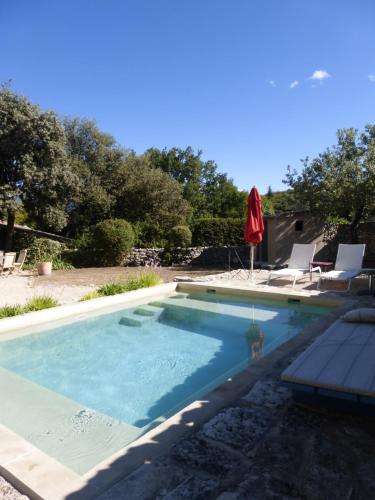 - une piscine avec un parasol rouge et des chaises dans l'établissement Mas Nicnac, à Blauvac