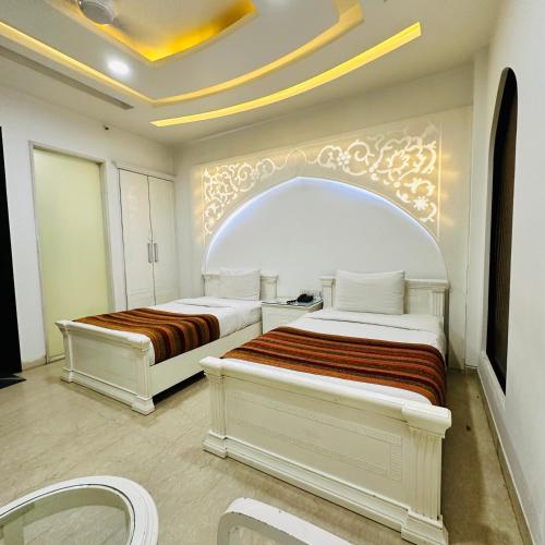 a bedroom with two beds in a room with a ceiling at Qotel Signature Lavish Rajouri Garden New Delhi in New Delhi