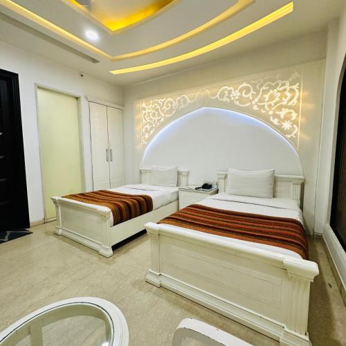 two beds in a white room with avisor at Qotel Signature Lavish Rajouri Garden New Delhi in New Delhi