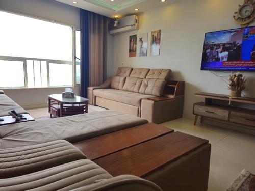 a living room with a couch and a flat screen tv at Gleem Luxury Condo Direct Sea view G18 in Alexandria