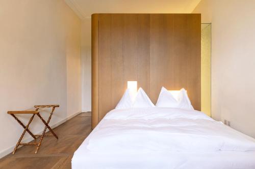 a bedroom with a white bed with a wooden headboard at Hotel St Petersinsel in Sankt Petersinsel