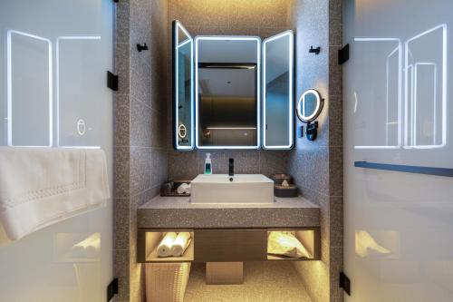 a bathroom with a sink and a mirror and a door at Atour S Hotel Lanzhou Guanghui East Red Square in Lanzhou