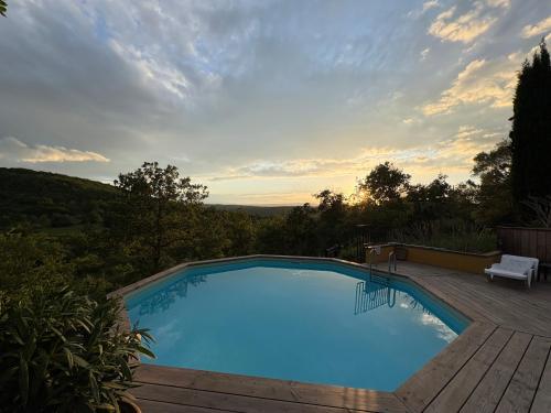 une grande piscine sur une terrasse en bois avec un banc dans l'établissement Villa Champie, à Pradons