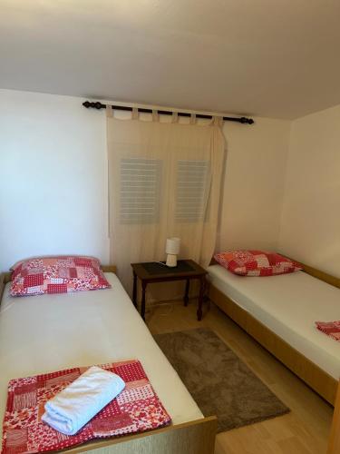 two twin beds in a room with a table at Apartman MAR in Mandre