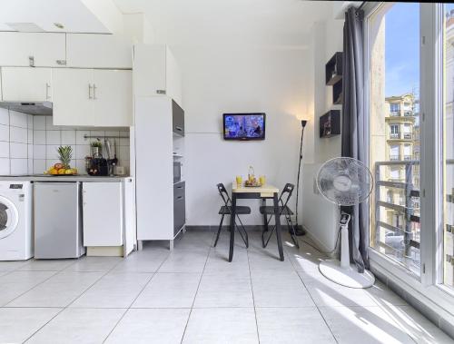 une cuisine blanche avec une table et une fenêtre dans l'établissement Hyper Center - Superb Studio - Cozy - Wifi, à Nice