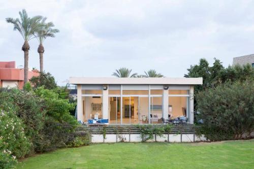 a house with palm trees in front of it at Beach House Galei in Herzliya B