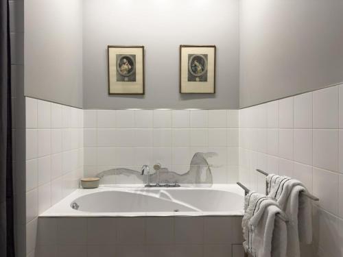 une salle de bain blanche avec une baignoire et deux tableaux encadrés dans l'établissement A beautiful designer apartment, à Cannes