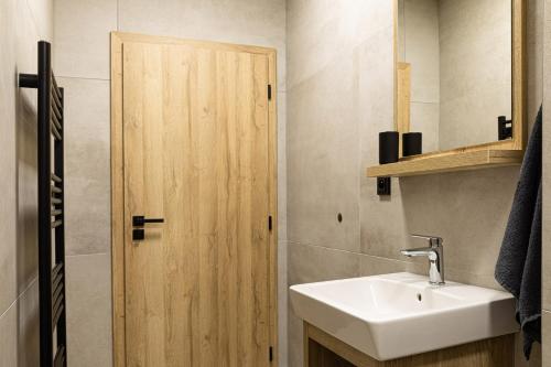 a bathroom with a sink and a wooden door at San Marco - Na Brněnské ulici in Mutěnice