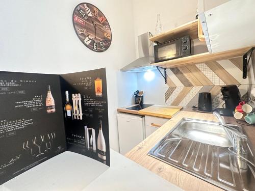 une cuisine avec un évier et une horloge murale dans l'établissement Talleyrand studio neuf cozy hyper centre, à Reims