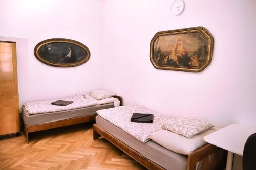 two beds in a room with paintings on the wall at At the Blue Lion & Parking Assistance in Prague