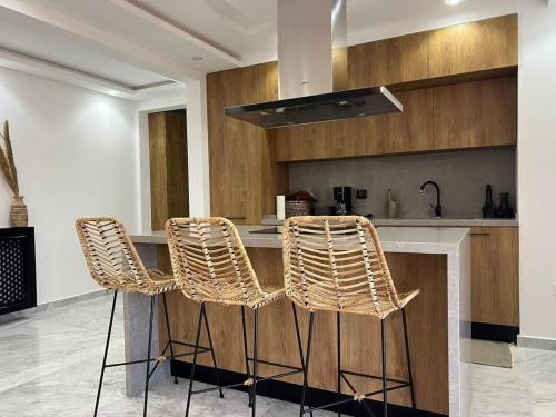 a kitchen with a counter with three rattan bar stools at Luxury 2 bedrooms apartment in kantaoui in Bin Rhilouf