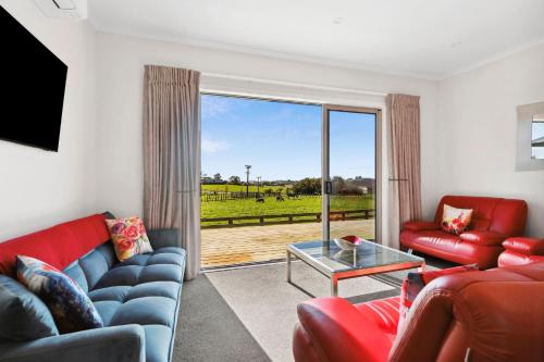 a living room with red furniture and a sliding glass door at Country Comfort - only 10 minutes from Hamilton CBD in Hamilton