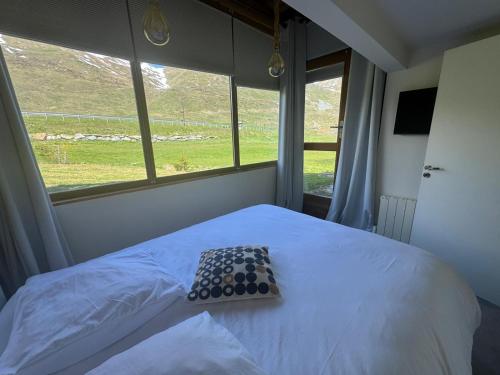 un lit dans une chambre avec une grande fenêtre dans l'établissement Dans Chalet aux Chartreux - T4 Duplex 100m2 traversant Vue Lac - Fibre, Golf, à Tignes