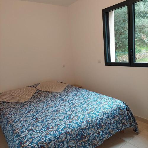 une chambre avec un lit avec une couette bleue et une fenêtre dans l'établissement Clos Jeannette Villa près de la plage de Pinarelle et des piscines naturelles du Cavu, à Zonza