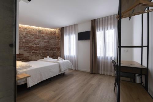 a bedroom with a white bed and a brick wall at Casa Castell Orangecosta in Peñíscola