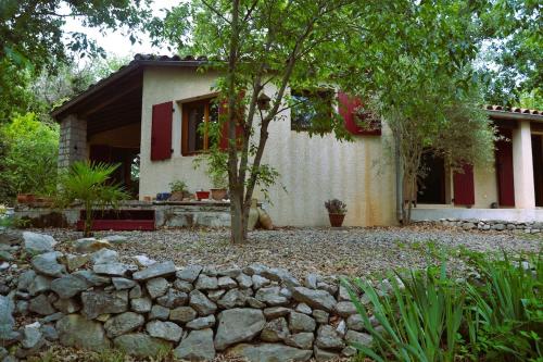 une maison avec un arbre devant dans l'établissement Maison sous les chênes, à Saint Alban Auriolles