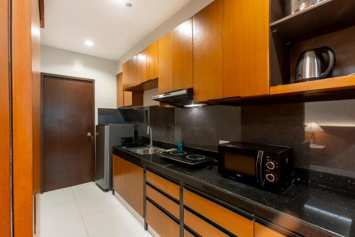 a kitchen with wooden cabinets and a microwave at Tropicana Suites in Manila