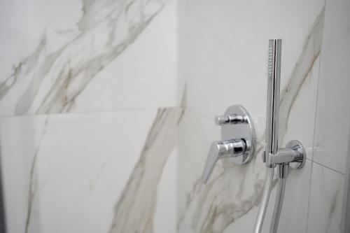 a shower in a bathroom with white marble walls at Bed and Breakfast Il Giardino in Amantea
