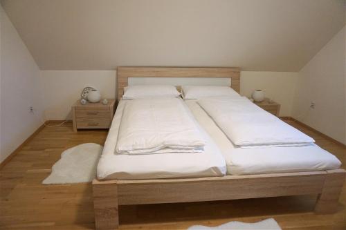 a bedroom with two beds with white sheets and wooden floors at Holiday home in a top location in Ferlach
