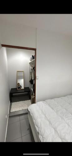 une chambre avec un lit blanc et un miroir dans l'établissement T2 Perier 13008, à Marseille
