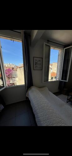 - une chambre avec deux fenêtres et un lit dans l'établissement T2 Perier 13008, à Marseille