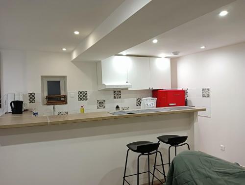 une cuisine avec deux tabourets de bar devant un comptoir dans l'établissement Gîte de la Fauvette, à Le Buisson Genois