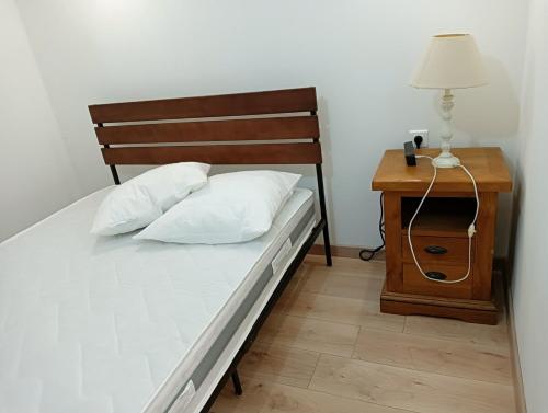 une chambre avec un lit et une table de chevet avec une lampe dans l'établissement Gîte de la Fauvette, à Le Buisson Genois