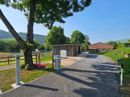 une porte sur une route avec un bâtiment et un arbre dans l'établissement Camping Onlycamp Les Monts du Cantal, à Le Claux