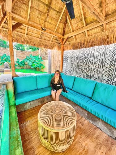 a woman sitting on a blue couch in a room at Villa Amuntai in Dinalupihan