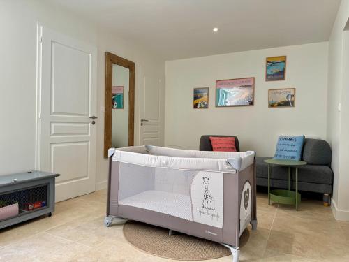 un lit bébé dans un salon avec une télévision dans l'établissement La Parenthèse Olonnaise & Maison Familiale, à LʼÎle-dʼOlonne