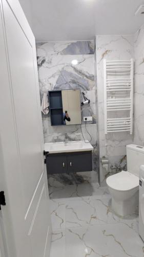 a white bathroom with a sink and a toilet at Gizo apartments in Batumi