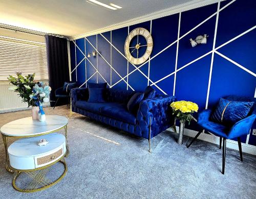a blue living room with blue couches and a clock at Luxury Modern Comfy 3BR House Contractors Family in Kettering
