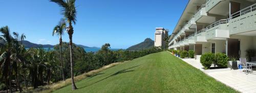 a large building with palm trees and a green lawn at Poinciana 112 Bedrooms x3 Free Buggy in Hamilton Island