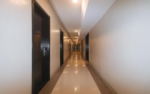 a hallway with a long corridor with white walls and a door at Iloilo Gateway Hotel and Suites by RedDoorz in Pavia