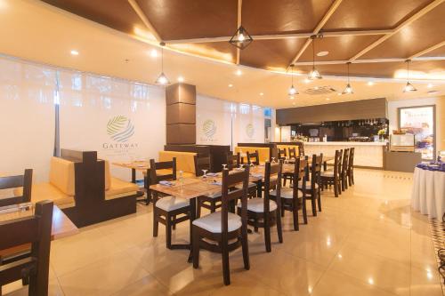 a restaurant with wooden tables and chairs and a counter at Iloilo Gateway Hotel and Suites by RedDoorz in Pavia